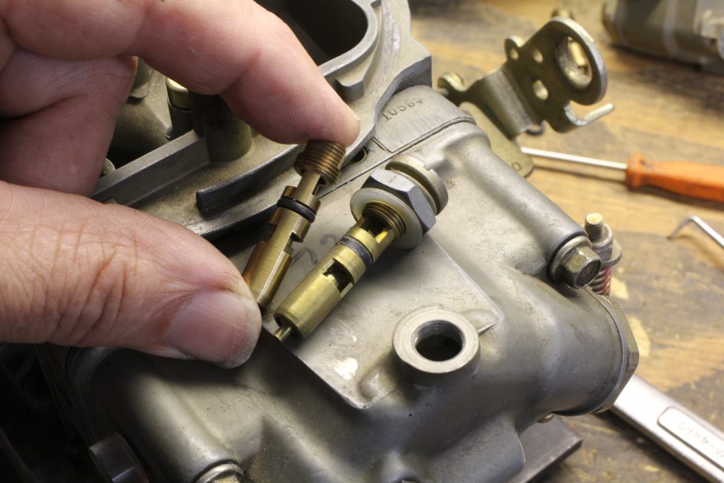 man holding needle and seat assembly near holley carburetor