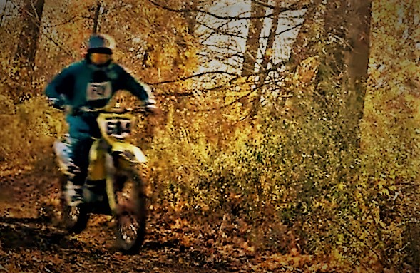 Man Racing dirt bike down trail