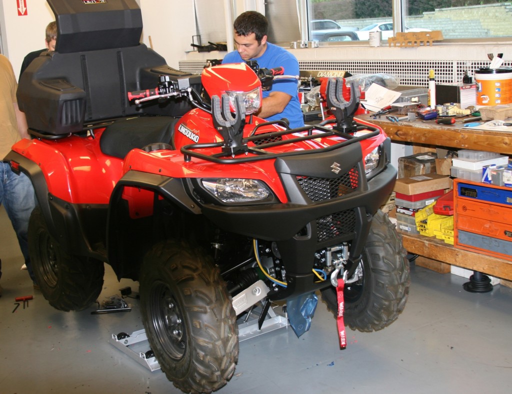 men servicing a utility atv in a garage