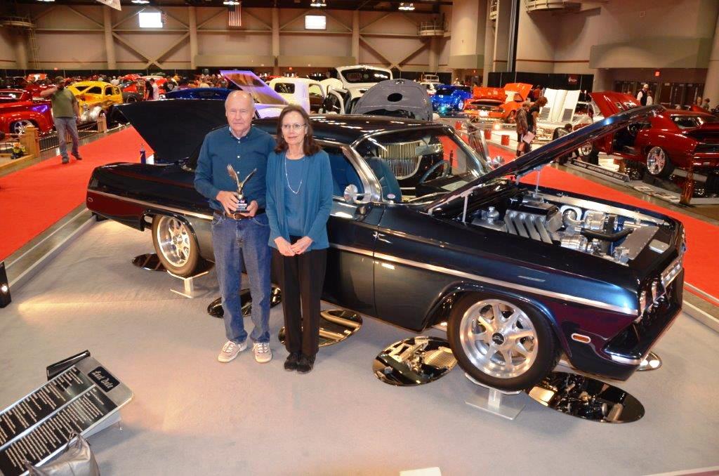 couple holding trophy next to 1962 chevy