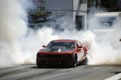 a fifth gen camaro doing a burnout at a dragstrip