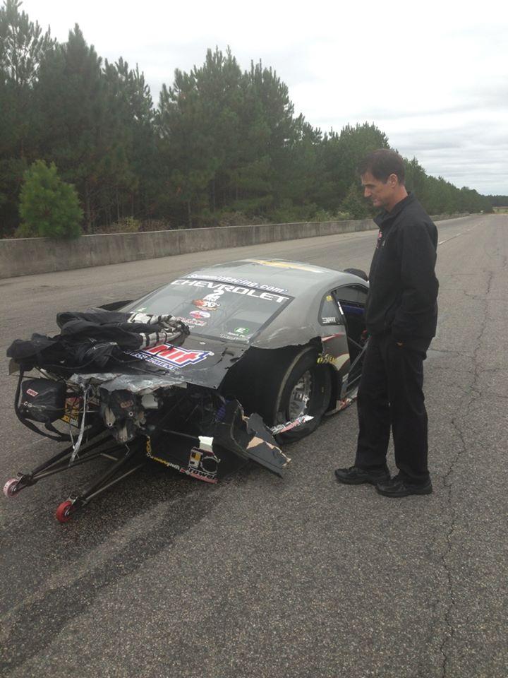 man inspecting crash wreckage of an nhra pro stock drag race car