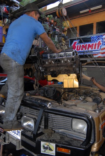 man putting an engine in an old truck