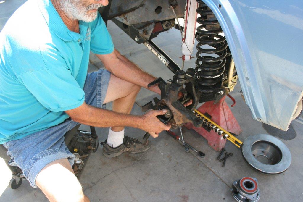 man installing axle shafts into the front axle of a jeep cherokee