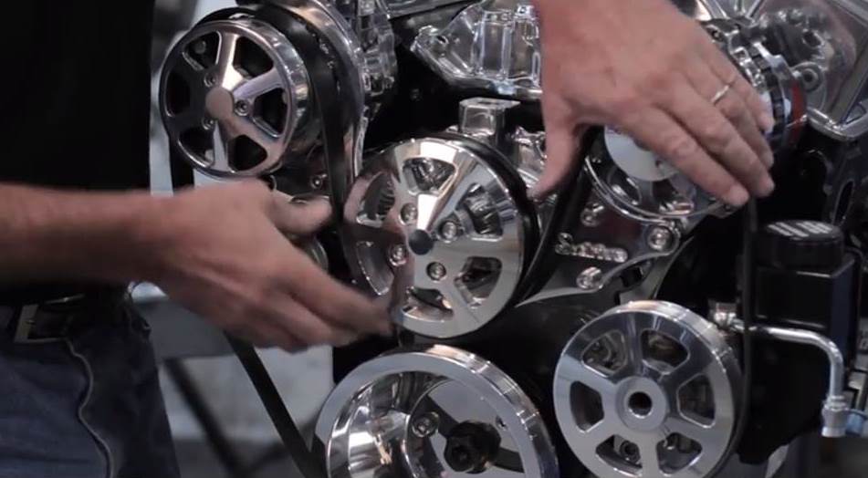 man installing a serpentine belt drive system on a v8 engine