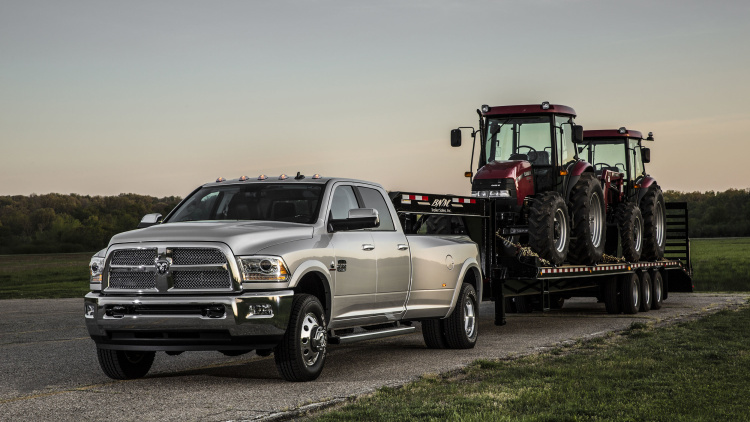 ram truck pulling a pair of tractors on a flatbed trailer