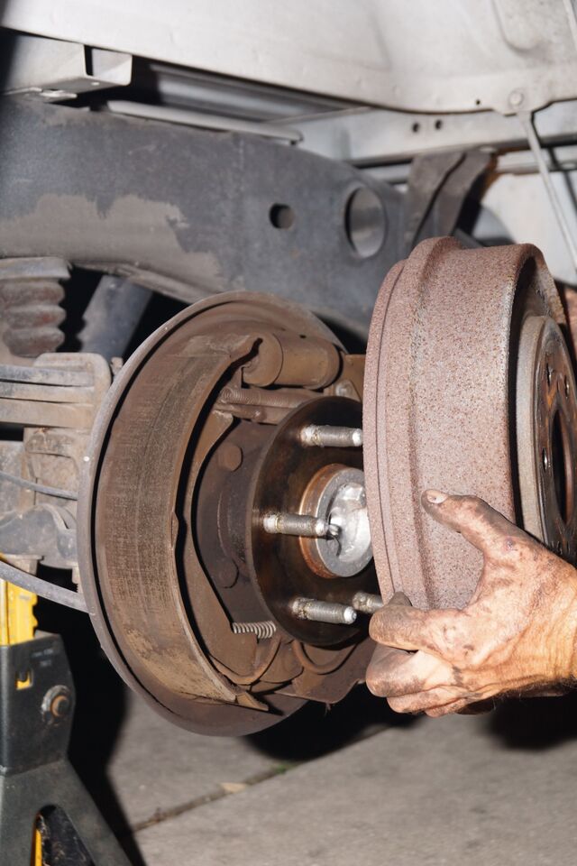 man removing drum from brake shoes and hub