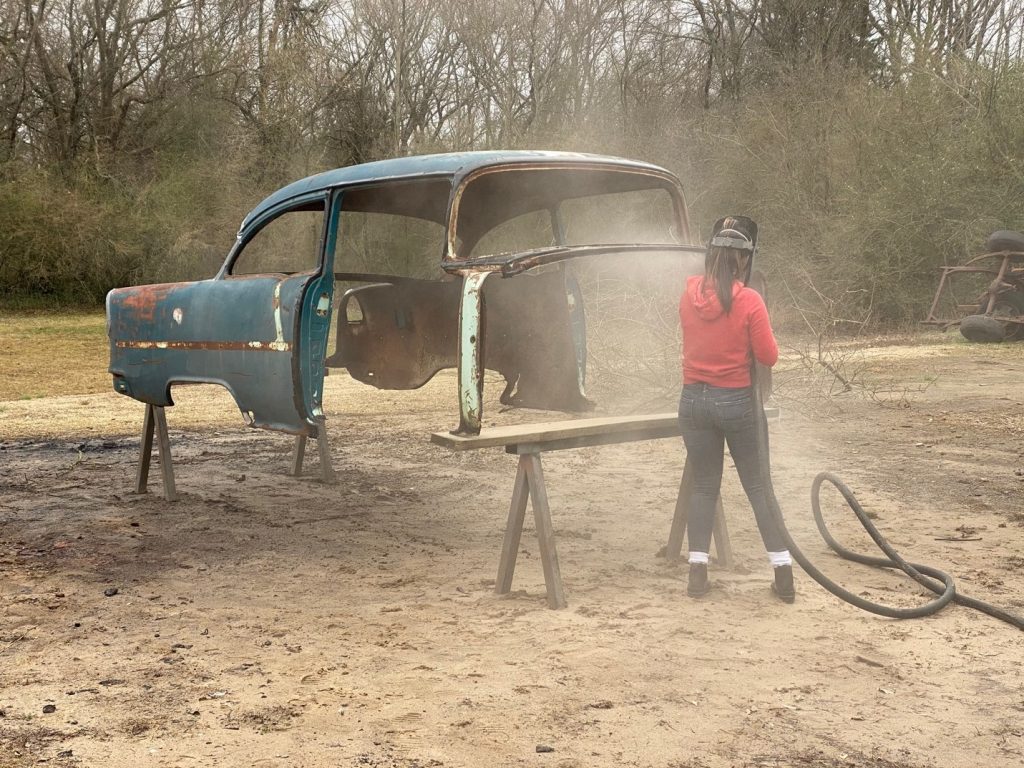 person sandblasting a 1955 chevy body prior to bodywork