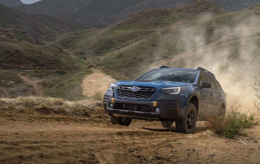 2022 subaru outback driving up a dusty mountain trail