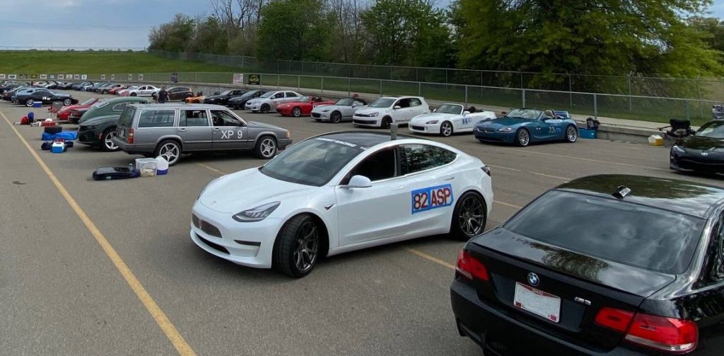 tesla model 3 parked among rows of autocross race cars