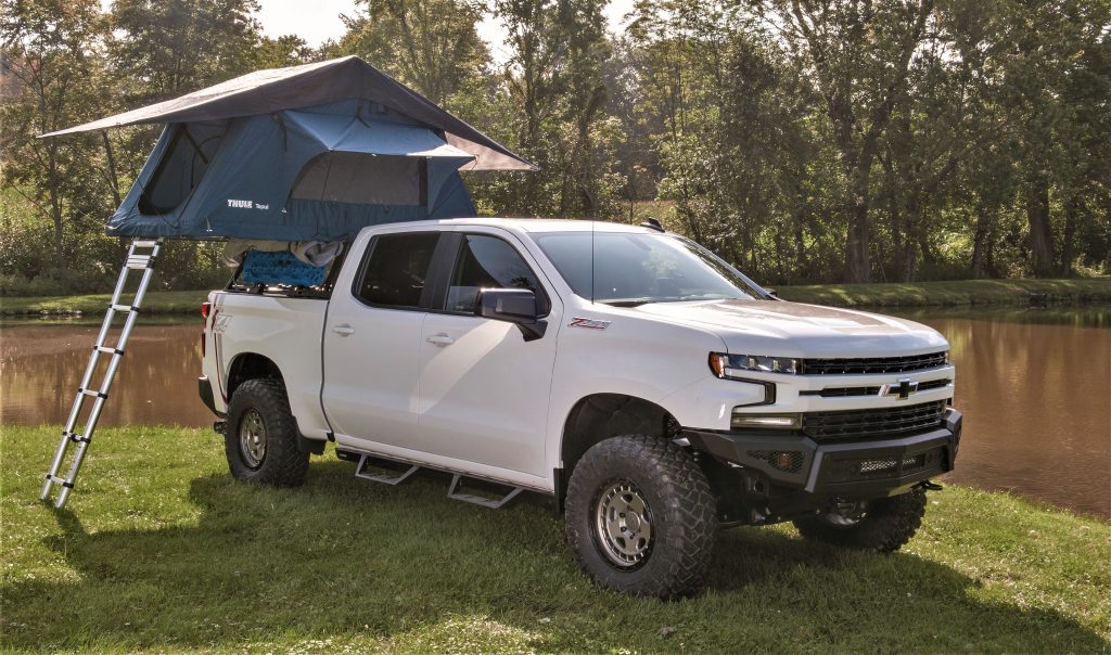 a chevy Silverado truck overlanding rig next to a small pond