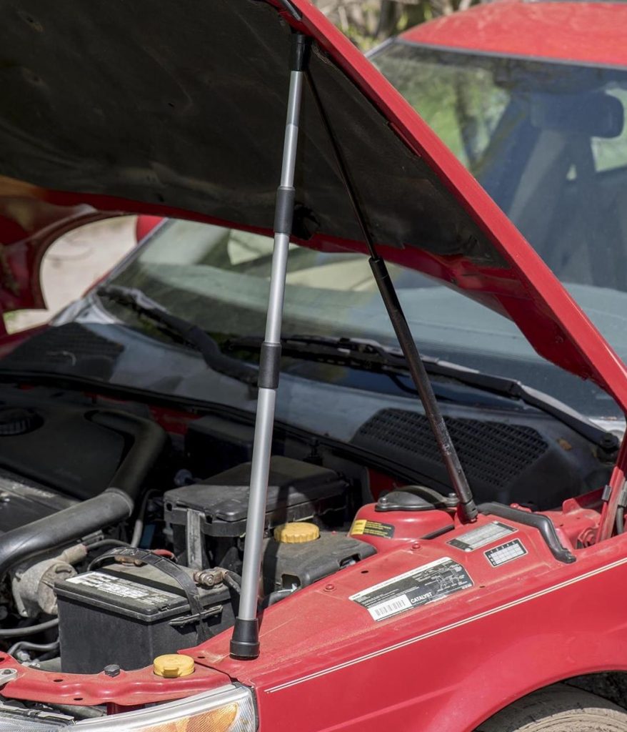 Red car with a hood being held up by an OEM hood prop rod