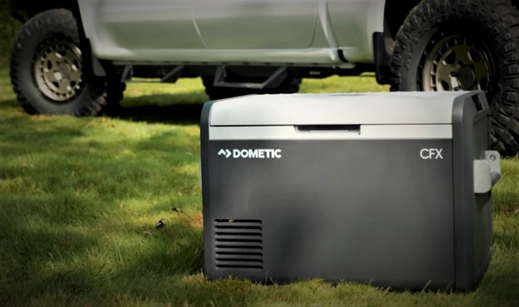 powered dometic cooler refrigerator with lid closed in front of truck at campsite