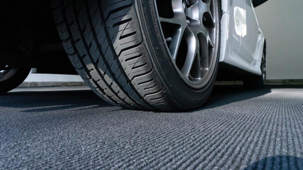 car wheel rolling on top of garage grip floor covering