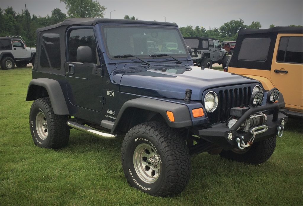 a blue jeep wrangler tj parked on grass