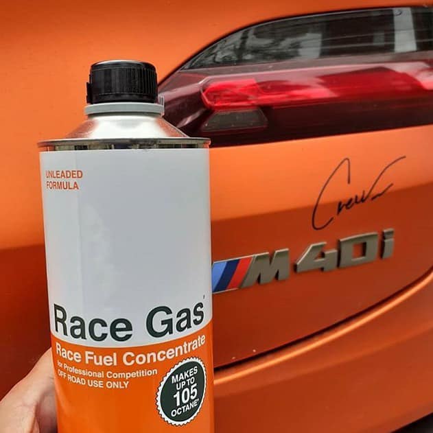 can of race gas in front of orange BMW car