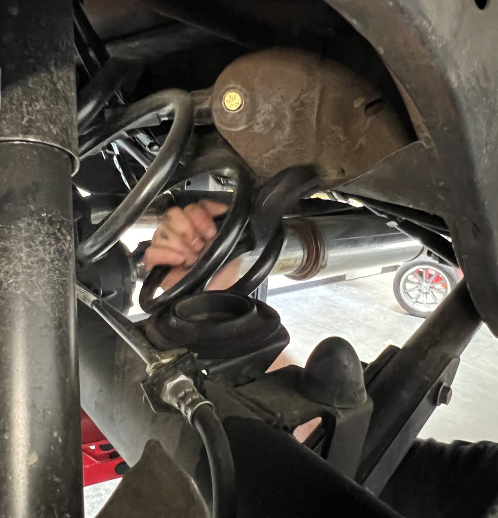 man removing coil spring from rear suspension of a 1972 chevelle