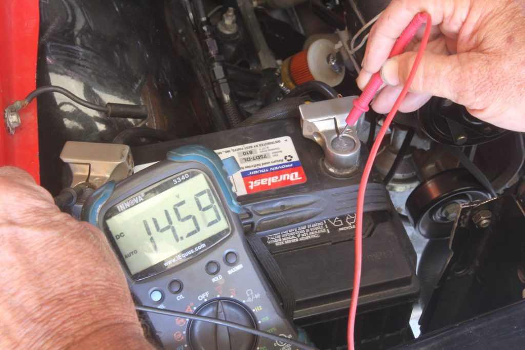 man testing battery alternator amp current draw on a car with a multimeter