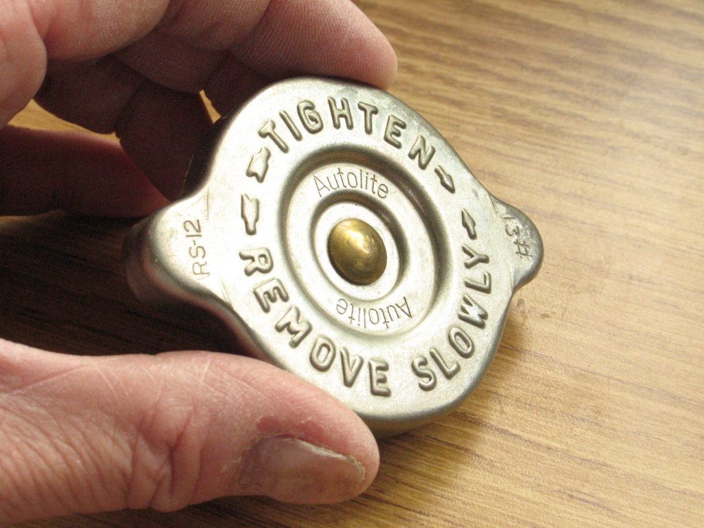 person holding a radiator cap