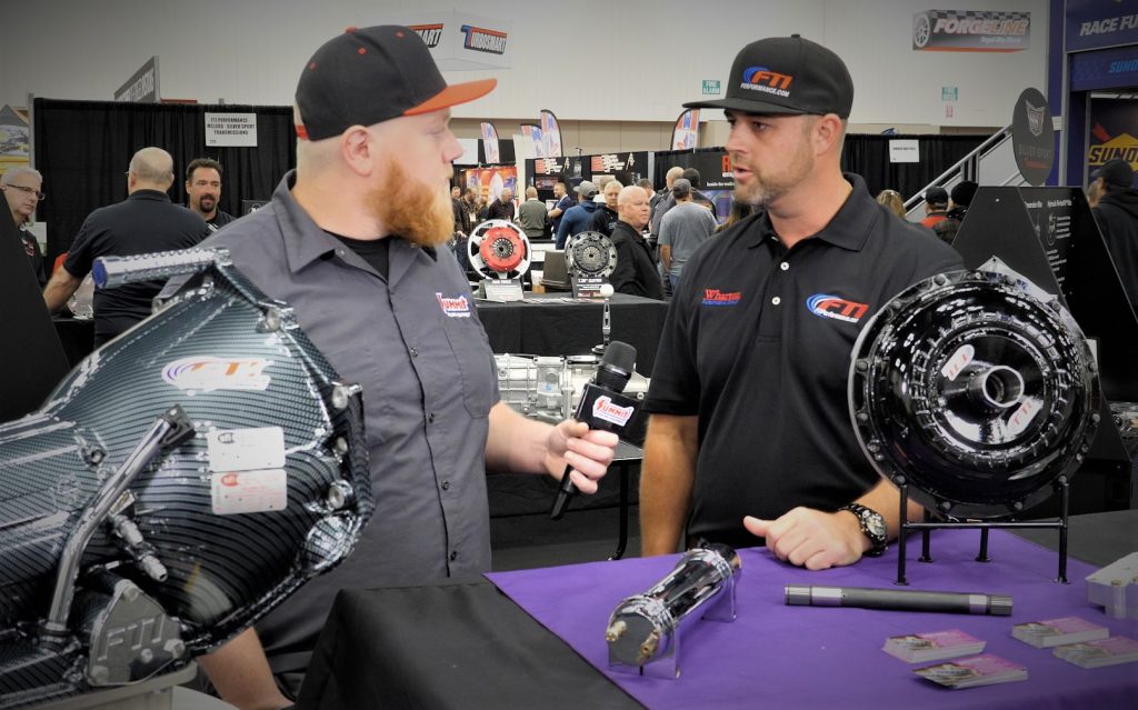 two men talking at a transmission booth at a trade show