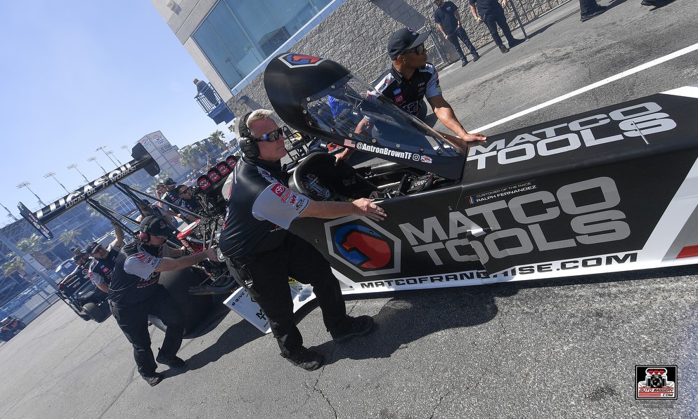 Antron Brown top fuel NHRA team pushing dragster to starting line