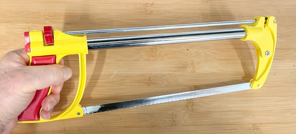 Man holding a hacksaw near a workbench