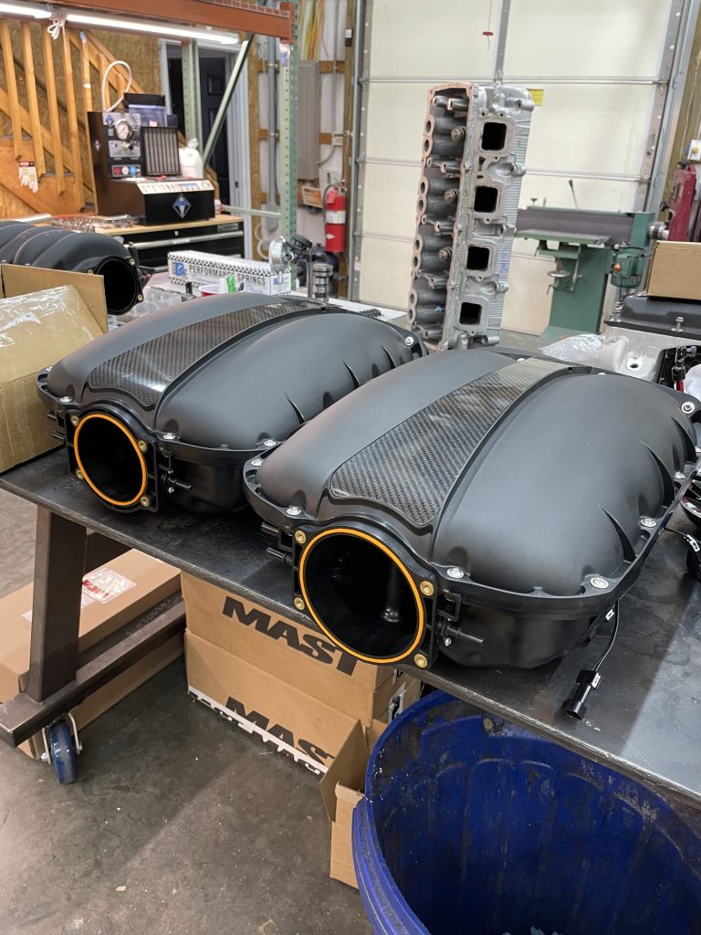 two ls engine intake manifolds sitting on a workbench
