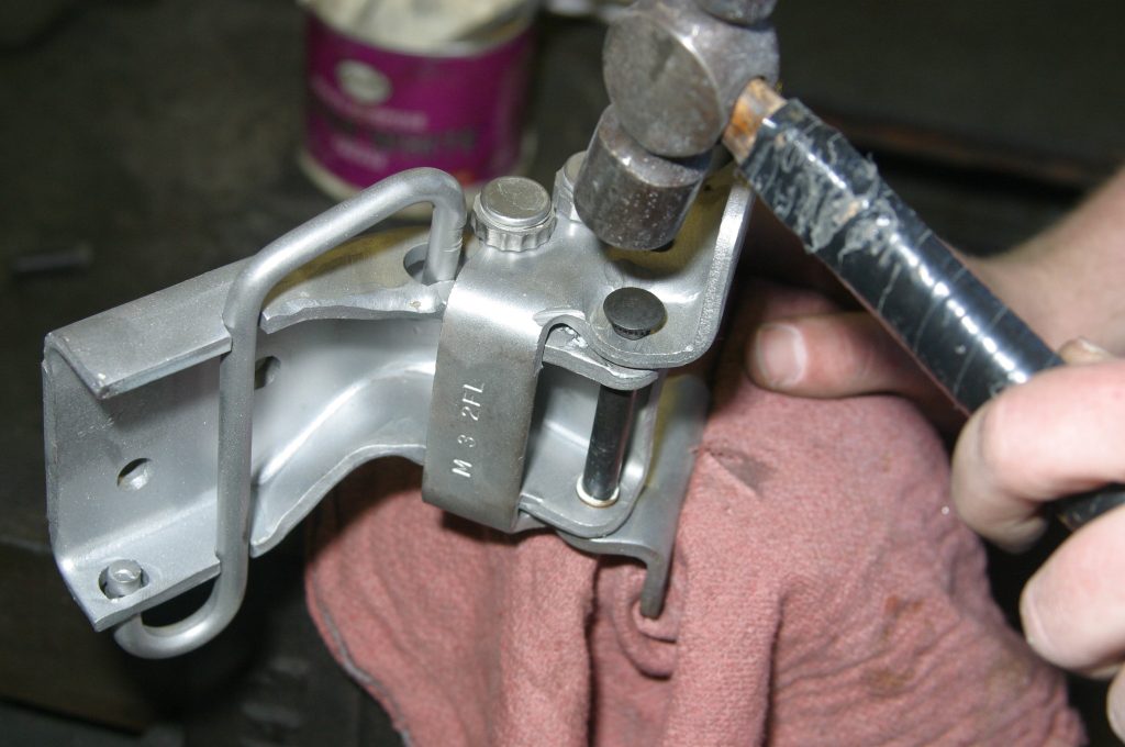 hammering a pin into a car door hinge