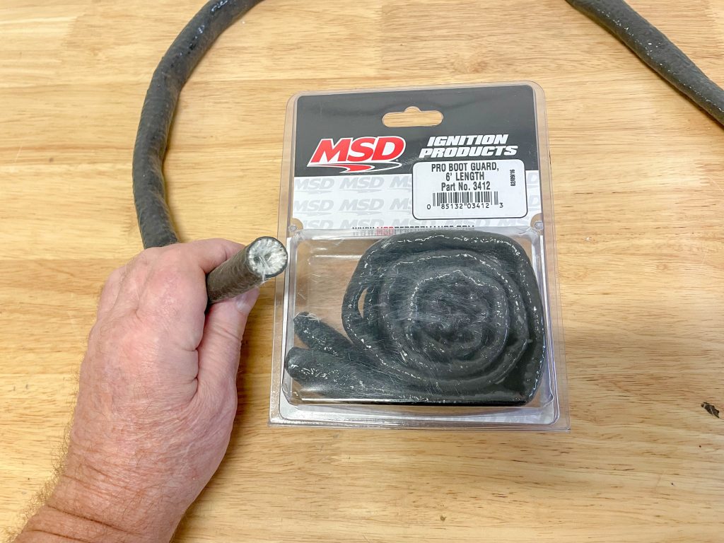 man holding msd spark plug boot guard heat wrap