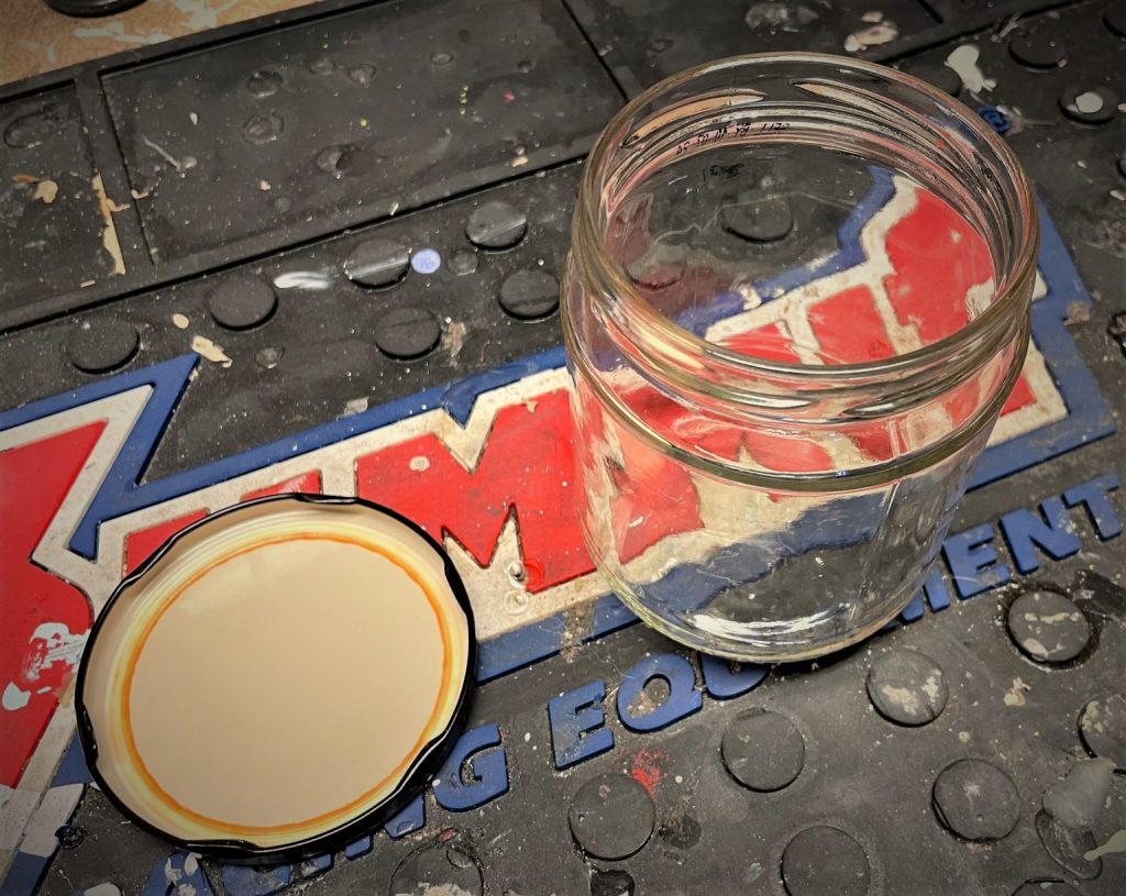 empty glass salsa jar and lid on workbench