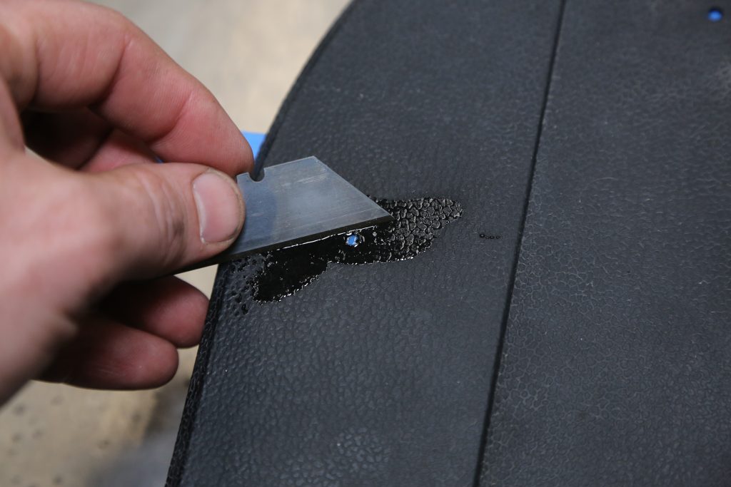 scraping epoxy off a trim panel with a razor blade