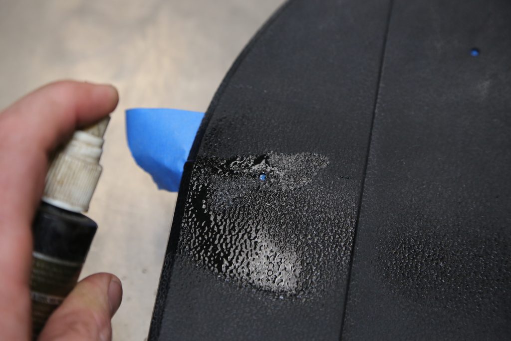 spraying cleaner on a plastic automotive panel