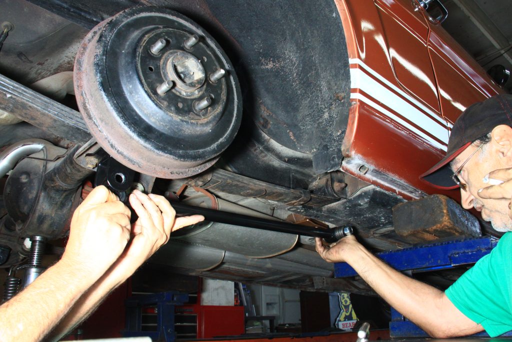 men installing a traction bar on a vintage mustang