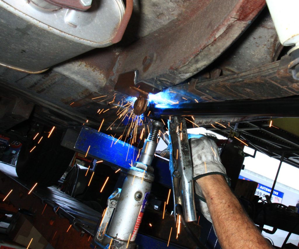 welding a metal mounting plate onto frame of old car