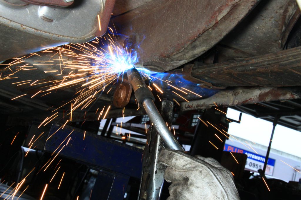 welding a mounting plate on the chassis of an old car
