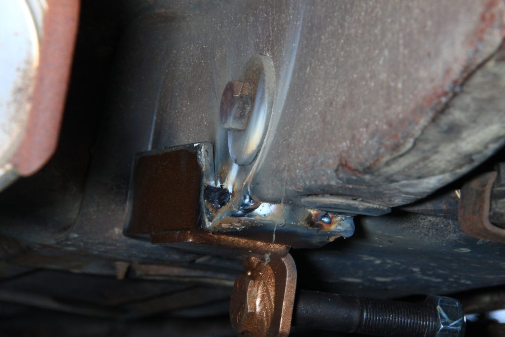 close up of a welded traction bar bracket on an old car