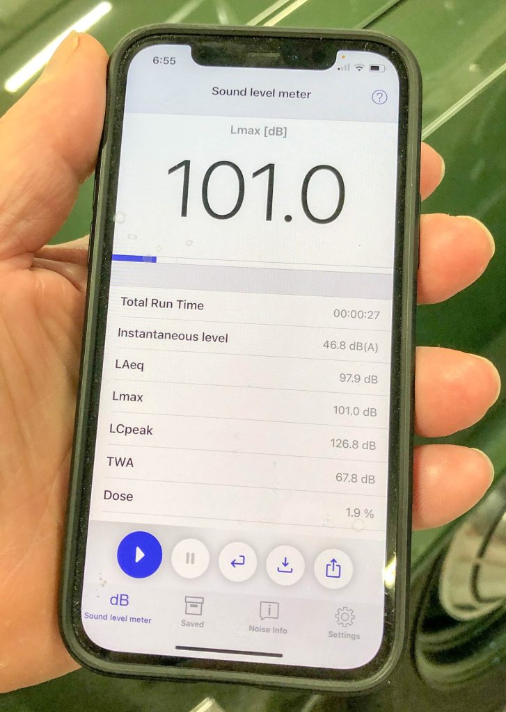man holding phone with sound level app displayed