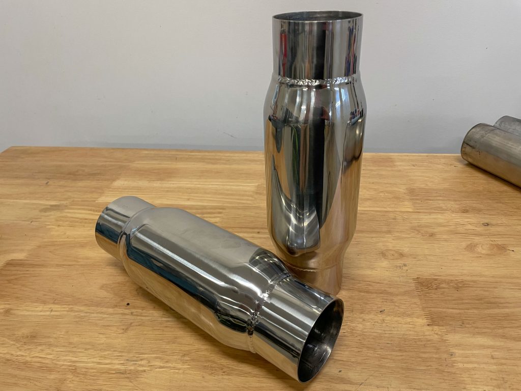 a pair of pass through mufflers on a workbench