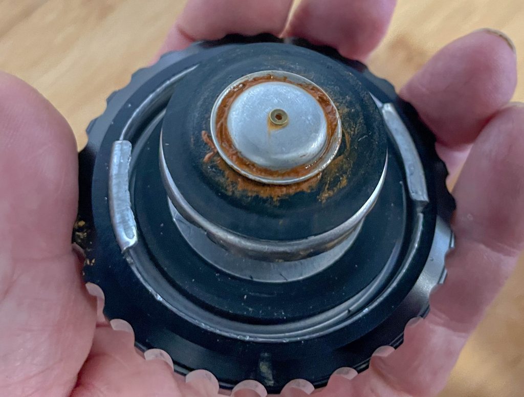 man holding a rusty radiator cap