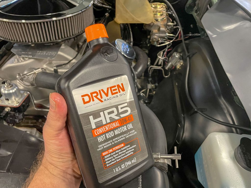 man holding a quart of motor oil near an engine