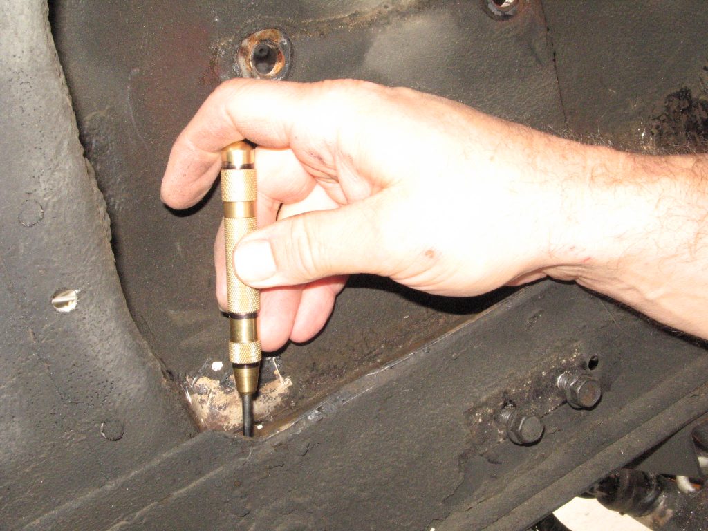using a small punch on a vintage mustang fender
