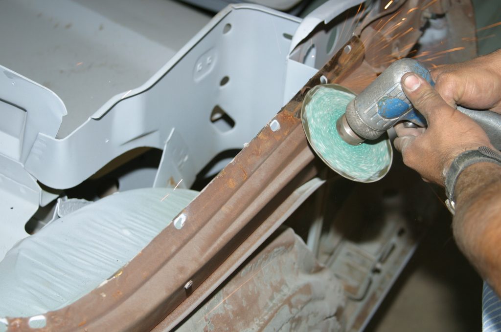 grinding down welds on a car panel