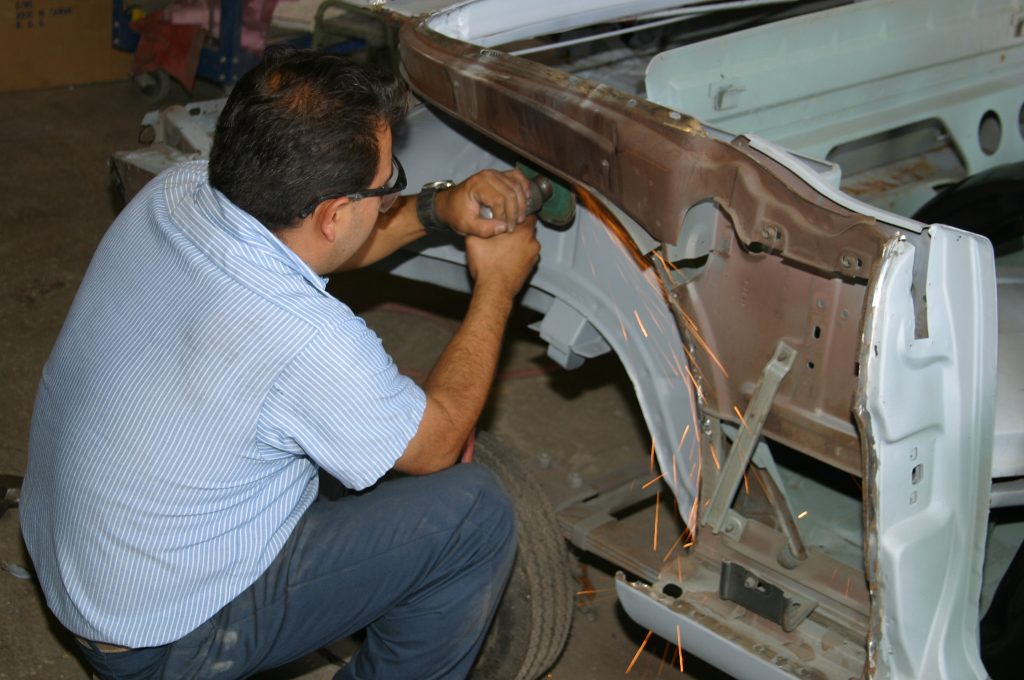 man cutting into a vintage car body