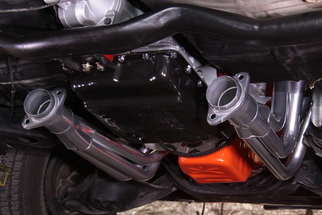 a set of headers exiting under a classic muscle car