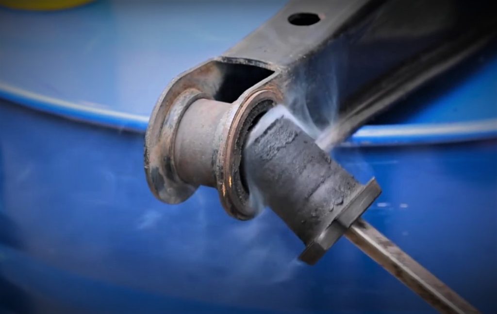 a superheated rubber bushing being removed from a control arm