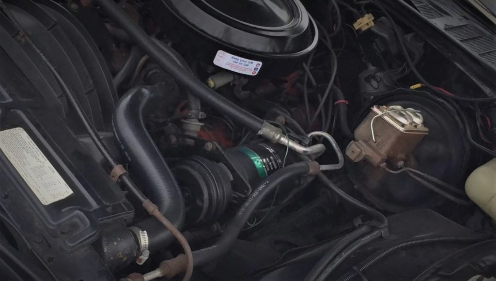 close up of hoses and rubber lines inside engine bay of an old car