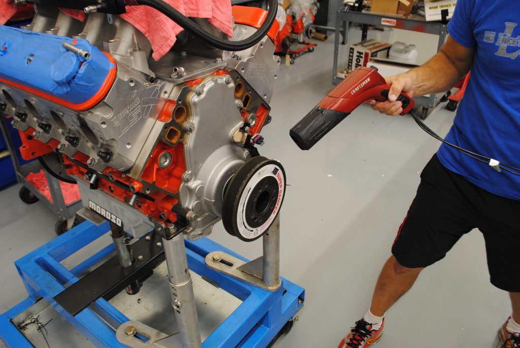 man holding timing light near a v8 engine on stand