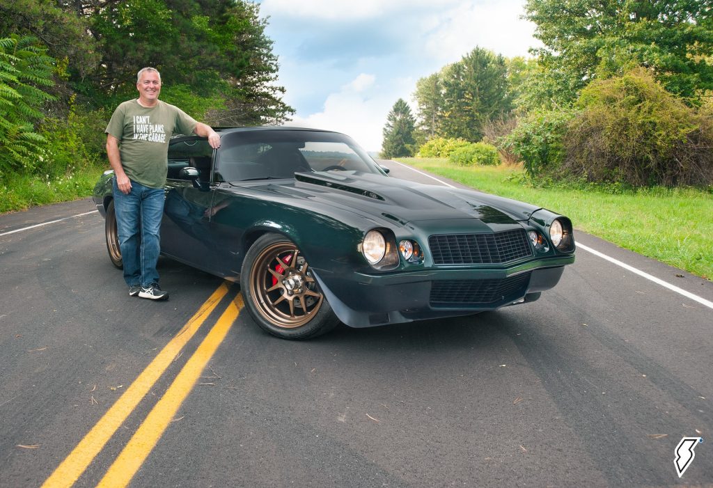 man standing next to a custom 1974 Chevy Camaro