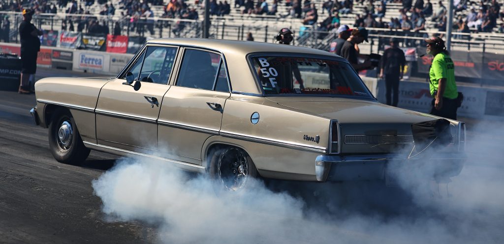 four door chevy nova doing a burnout at dragstrip